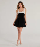 The Marilyn Bow Strap Velvet Skater Dress is a stunning black mini dress with a short hem, designed to be the perfect winter cocktail dress or night-out look for the holiday season.