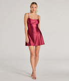 The Glistening Beauty Glitter Satin Mini Dress is a stunning raisin purple mini dress with a short hem, designed to be the perfect winter cocktail dress or night-out look for the holiday season.