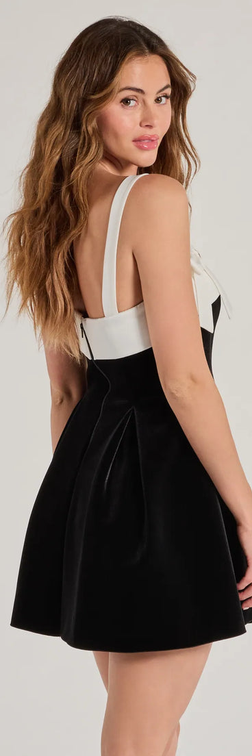 The Marilyn Bow Strap Velvet Skater Dress is a mini dress in black, perfect for an above-the-knee holiday party dress or a stylish NYE look, with a short hemline designed to make a winter statement.