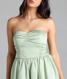 Step into summer looking effortlessly chic in the Lorena Satin Strapless Skater Dress in sage green, a must-have Windsor dress for your warm-weather wardrobe.