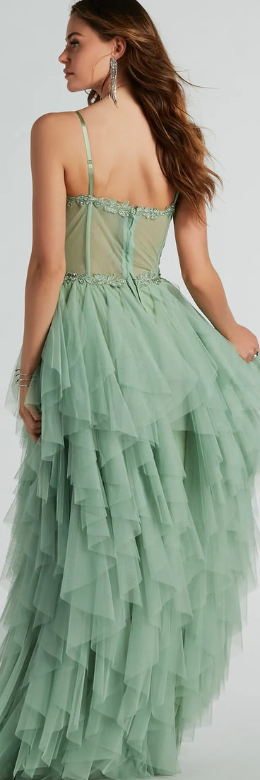 The Keyla Floral Applique Tiered Ruffle Tulle Gown in sage is a stunning green prom dress designed to capture attention with its fresh or bold color and effortlessly stylish silhouette.