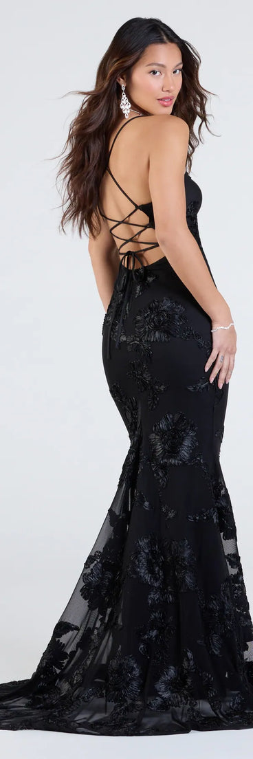 The Gabi Lace-Up Floral Trim Mermaid Formal Dress is a show-stopping black prom dress, offering a sleek, slimming silhouette that enhances your natural beauty for an unforgettable night.