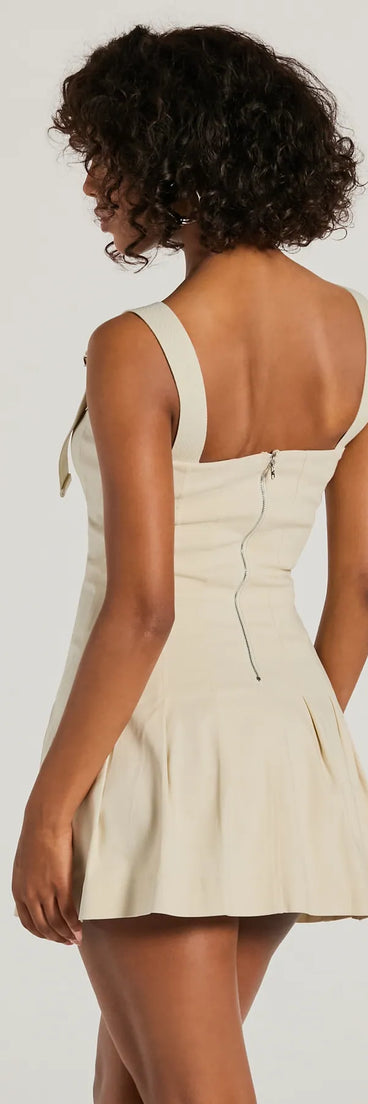 The Babe With Taste Buckle Strap Pleated Mini Dress is a mini dress in taupe, perfect for an above-the-knee holiday party dress or a stylish NYE look, with a short hemline designed to make a winter statement.