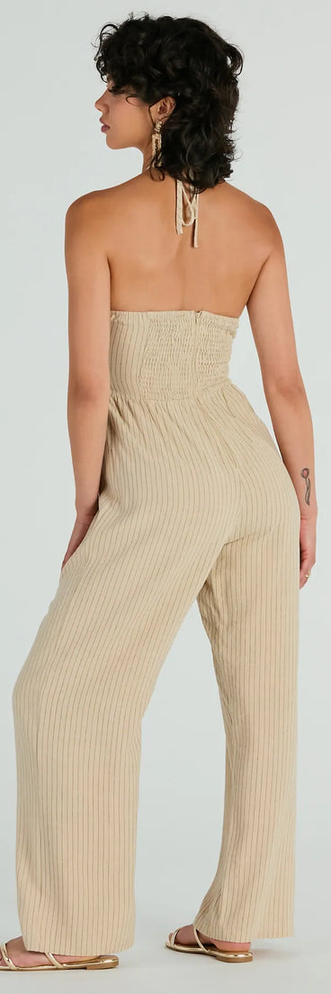 The Coastal Cutie Halter Cutout Striped Linen Jumpsuit in taupe is a versatile women's jumpsuit with trendy design accents, crafted for holiday-ready looks, from office wear to sophisticated winter night outs.