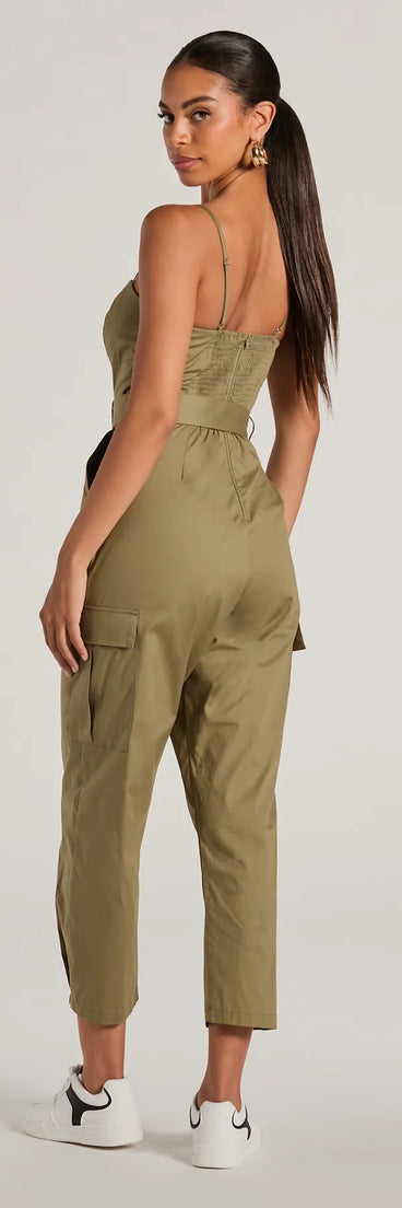 The Social Outing Sleeveless Belted Cargo Crop Jumpsuit in olive is a versatile women's jumpsuit with trendy design accents, crafted for holiday-ready looks, from office wear to sophisticated winter night outs.