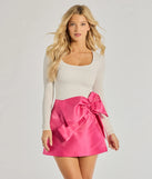The Adorable Muse Bow Detail Mini Skirt is a trendy women's bottom in fuchsia, designed with modern details and alluring textures to complete chic outfits for 2025.