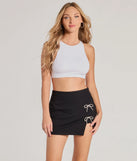 The Exceptionally Precious Rhinestone Bow Ponte Skort is a trendy women's bottom in black, designed with modern details and alluring textures to complete chic outfits for 2025.