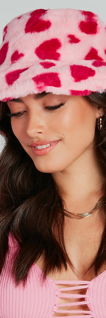 Whether you're dressing up for a romantic date or a Galentine's event, the Heart For Cozy Faux Fur Bucket Hat in pink is the perfect accessory to elevate your Valentine's Day outfit.