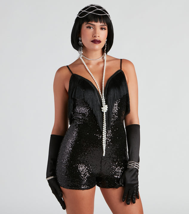 Women’s 1920's flapper costume styled with a black fringe romper, satin gloves, rhinestone costume jewelry, an extra long pearl necklace, and rhinestone headpiece 